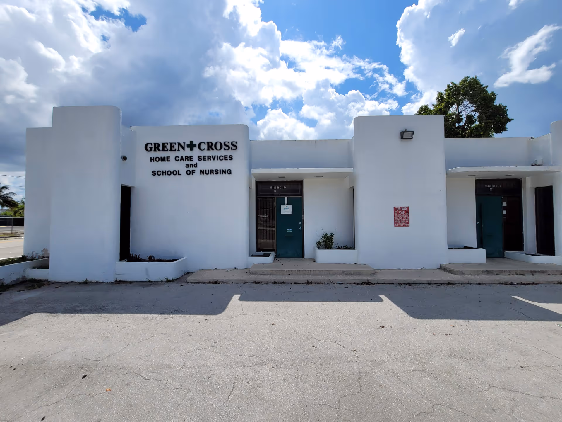White single story building exterior with Green Cross Home Care Services sign and entry doors