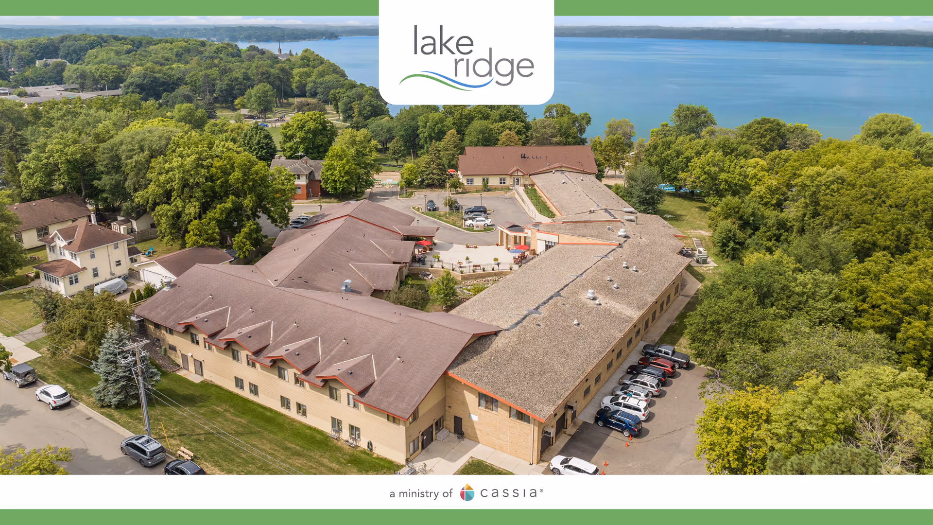 Aerial view of Lake Ridge Care Center of Buffalo with parking, trees, and lake.