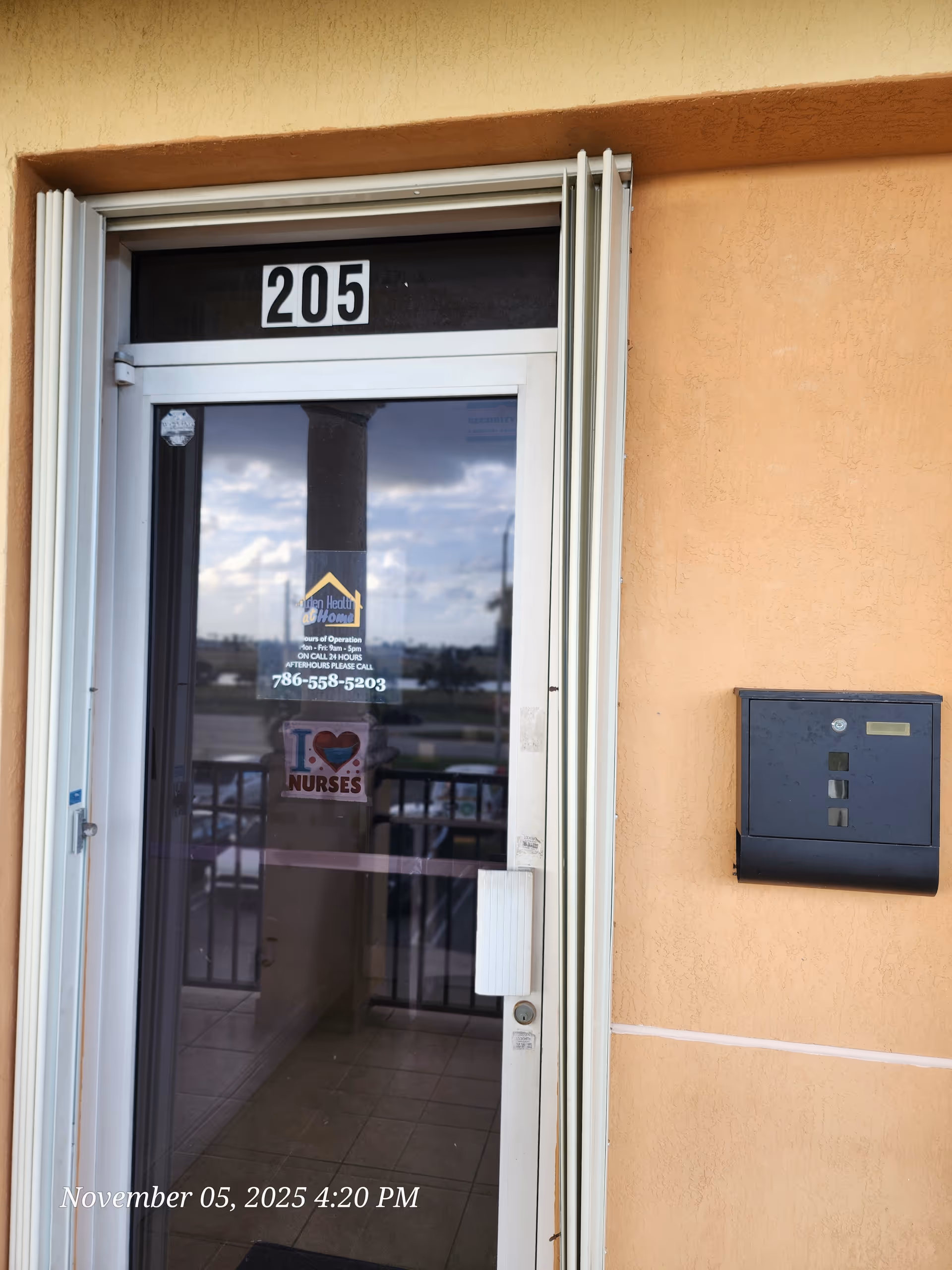 Entrance glass door to a senior living facility labeled 205 on an orange wall.