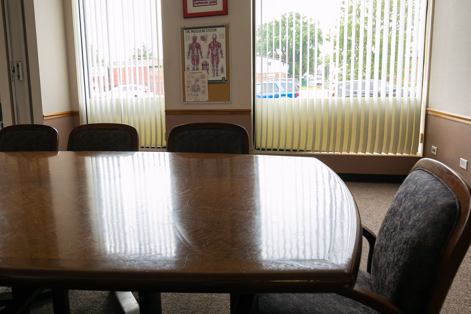 A large wooden table with chairs in a sunlit dining room.