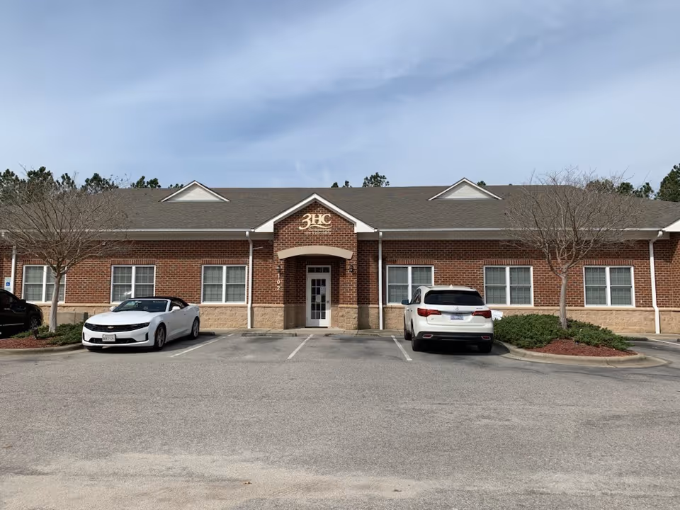 Brick front of 3HC Home Health & Hospice building with parked cars and bare trees.