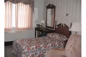 Two single beds with floral bedspreads, lamps, and a dresser in a vintage bedroom.