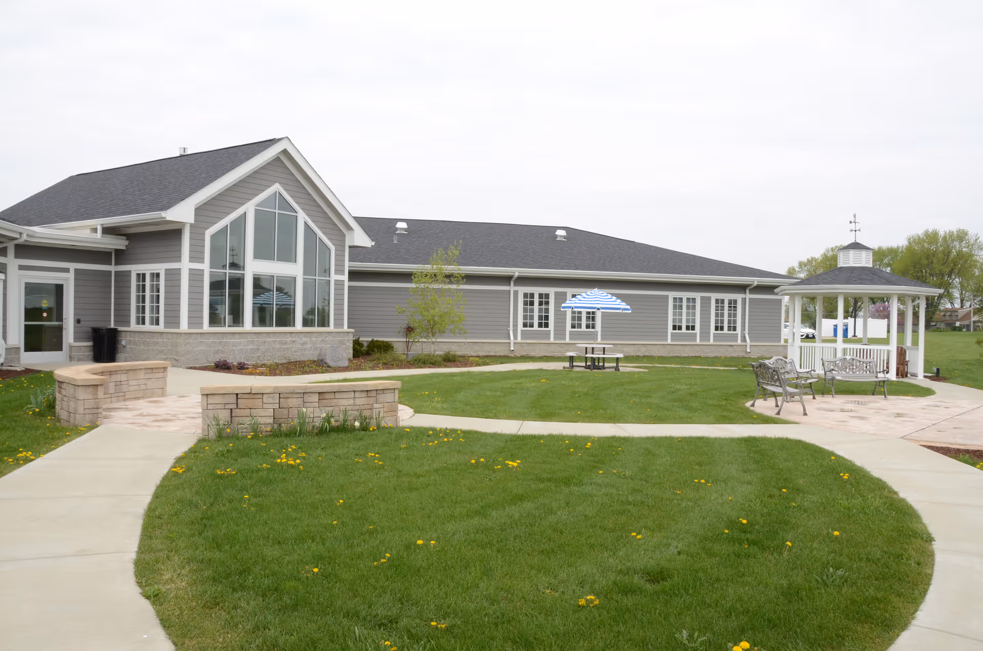 Exterior view of Rock River Hospice & Home with lawn, patio, and gazebo.