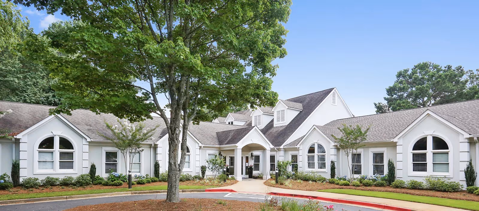 Exterior view of Radiance East Cobb, a white building with arched windows and landscaped entrance.