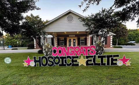 Front view of a hospice building with a large CONGRATS HOSPICE ELITE sign on the lawn.