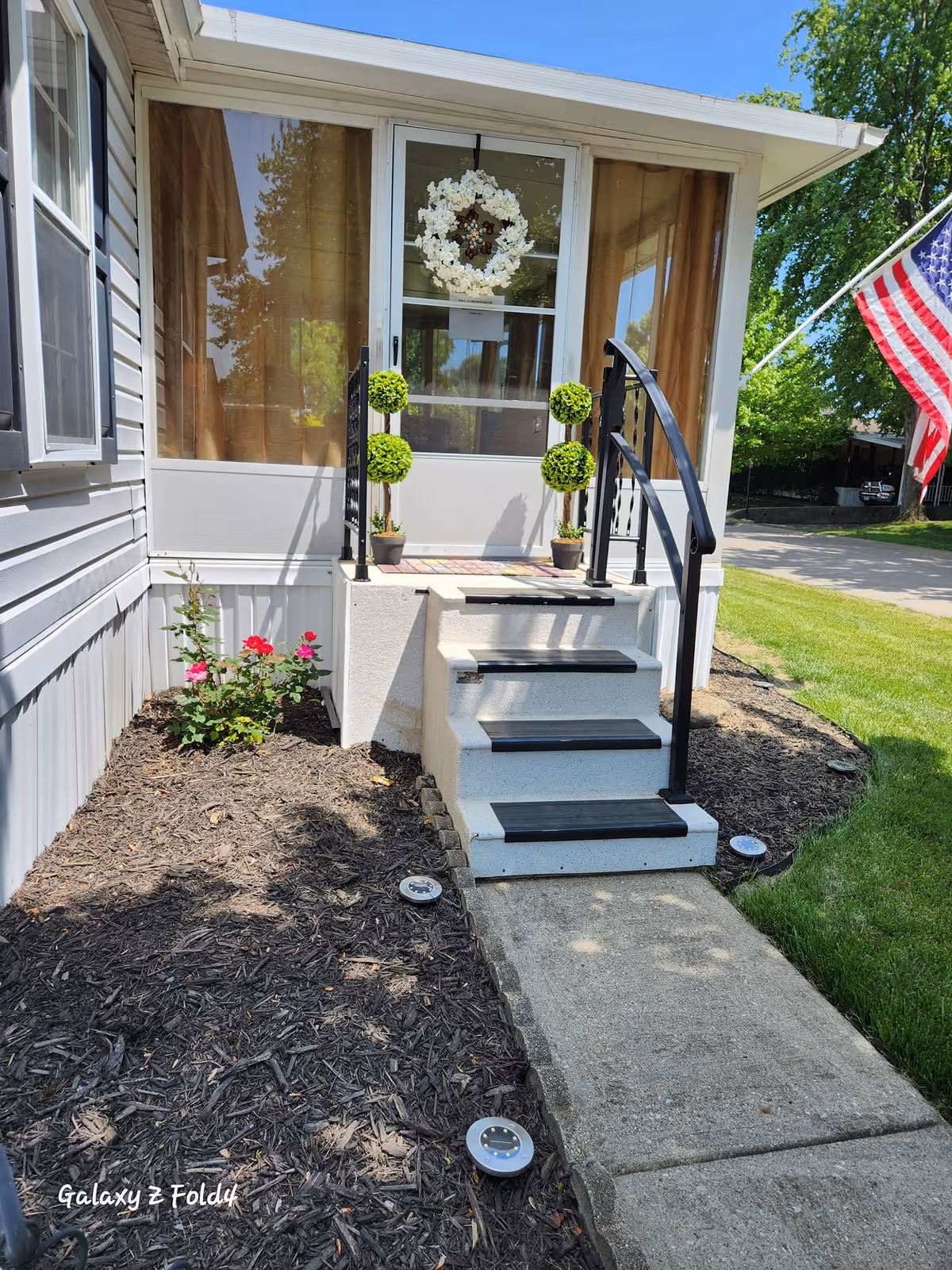 Front entrance of a senior living facility with wreath, potted topiaries, and an American flag.