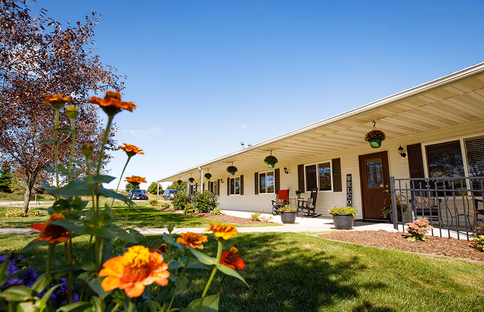 Exterior view of Countryside Manor showing a covered front porch with chairs and hanging planters.