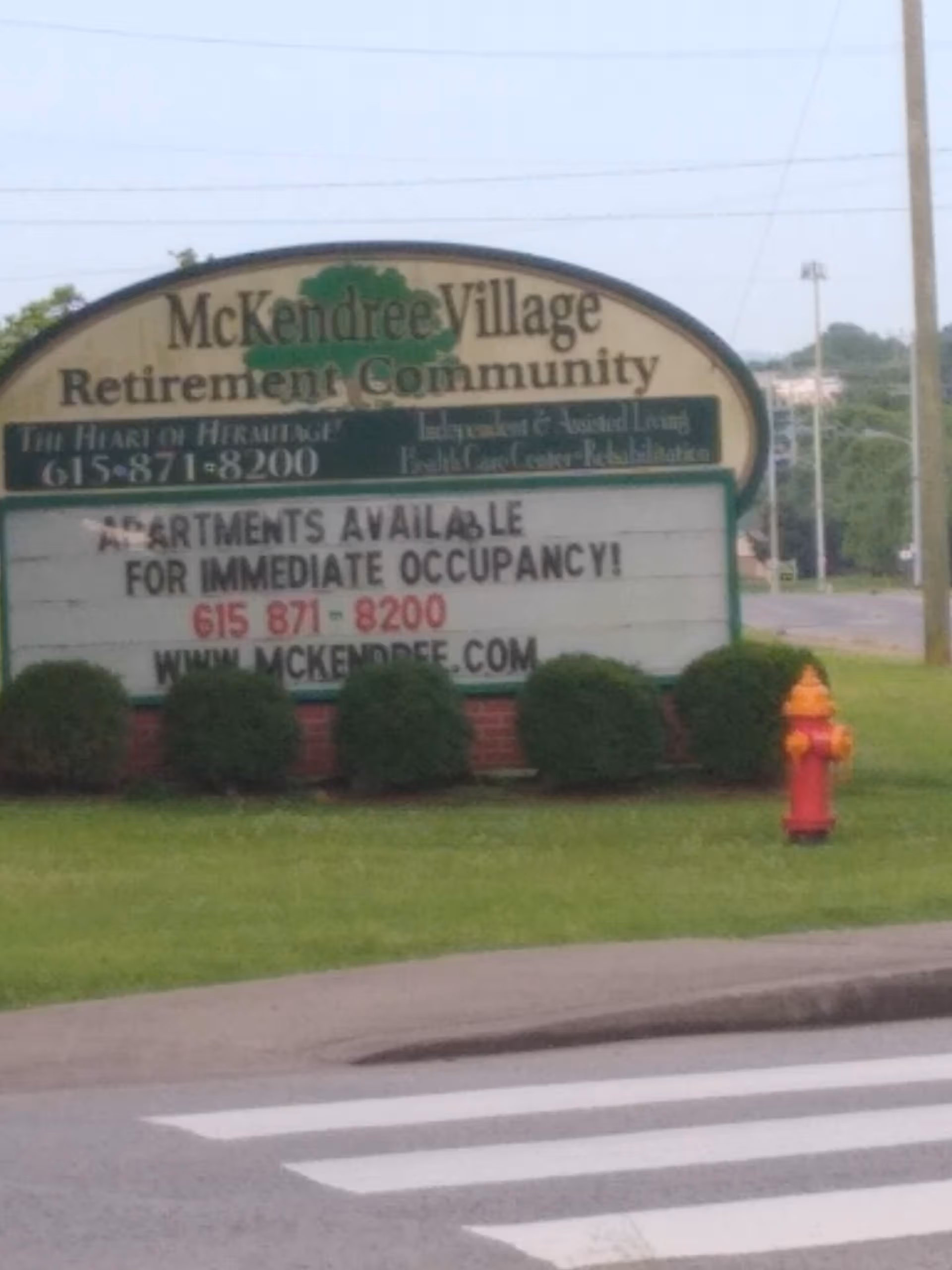 McKendree Village Retirement Community sign on a grassy front lawn with a fire hydrant