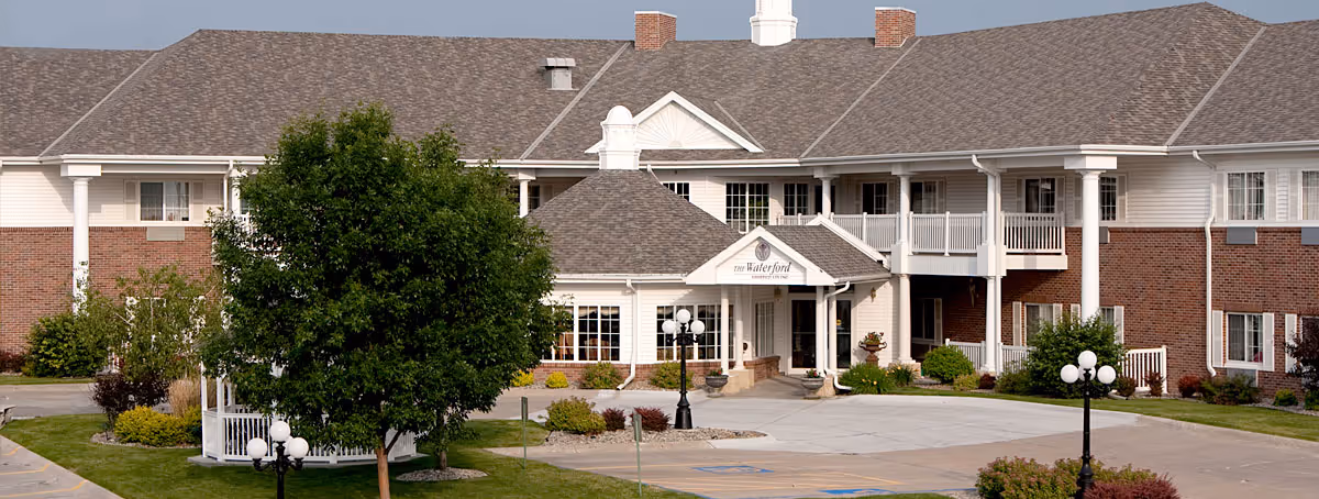 Waterford at Williamsburg exterior with brick and white siding, entrance, and landscaped grounds.