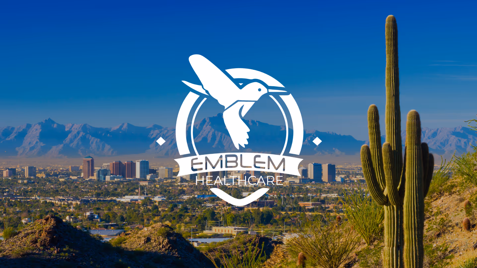 Desert city skyline with mountains, a tall cactus, and Emblem Healthcare logo.