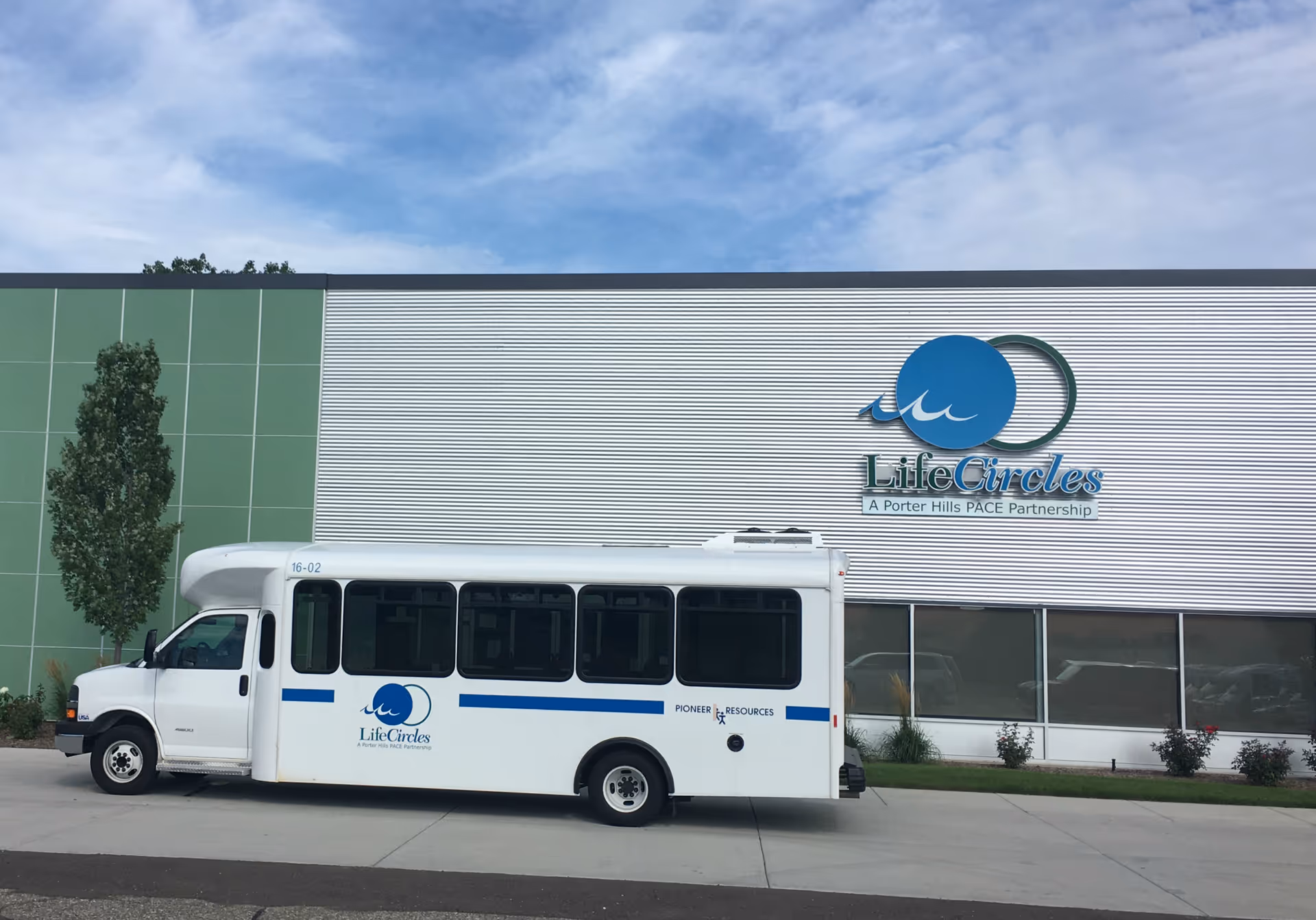 Front exterior of LifeCircles PACE facility with a parked white shuttle bus.