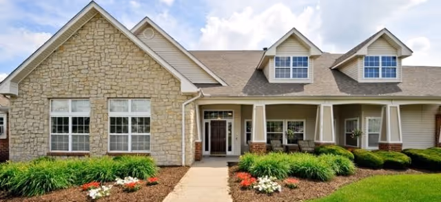 Exterior view of Brookdale Springdale featuring a stone facade, covered entrance, and landscaping.