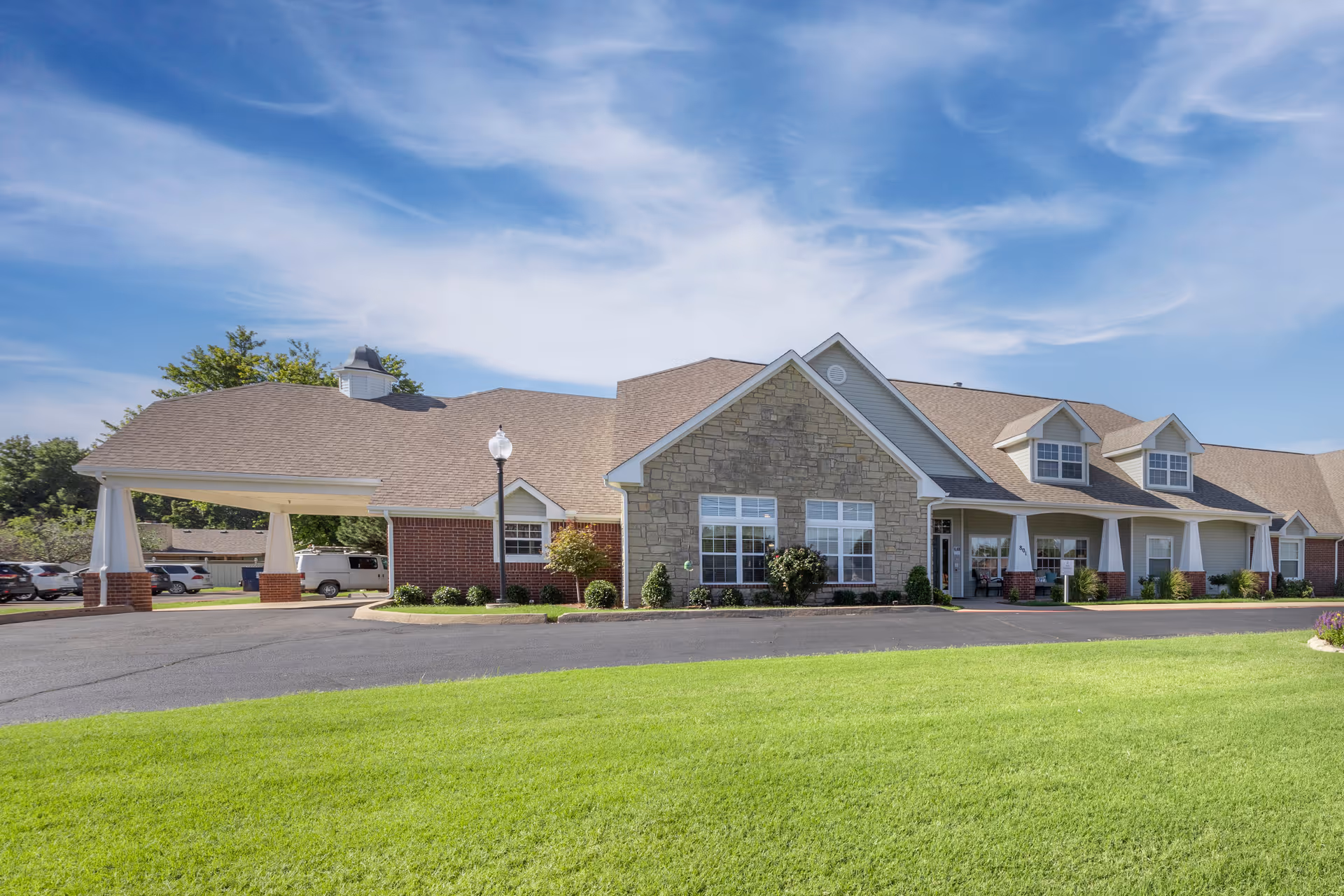 Brookdale Chickasha senior living facility exterior with entrance, stone facade, brick columns, and green lawn.