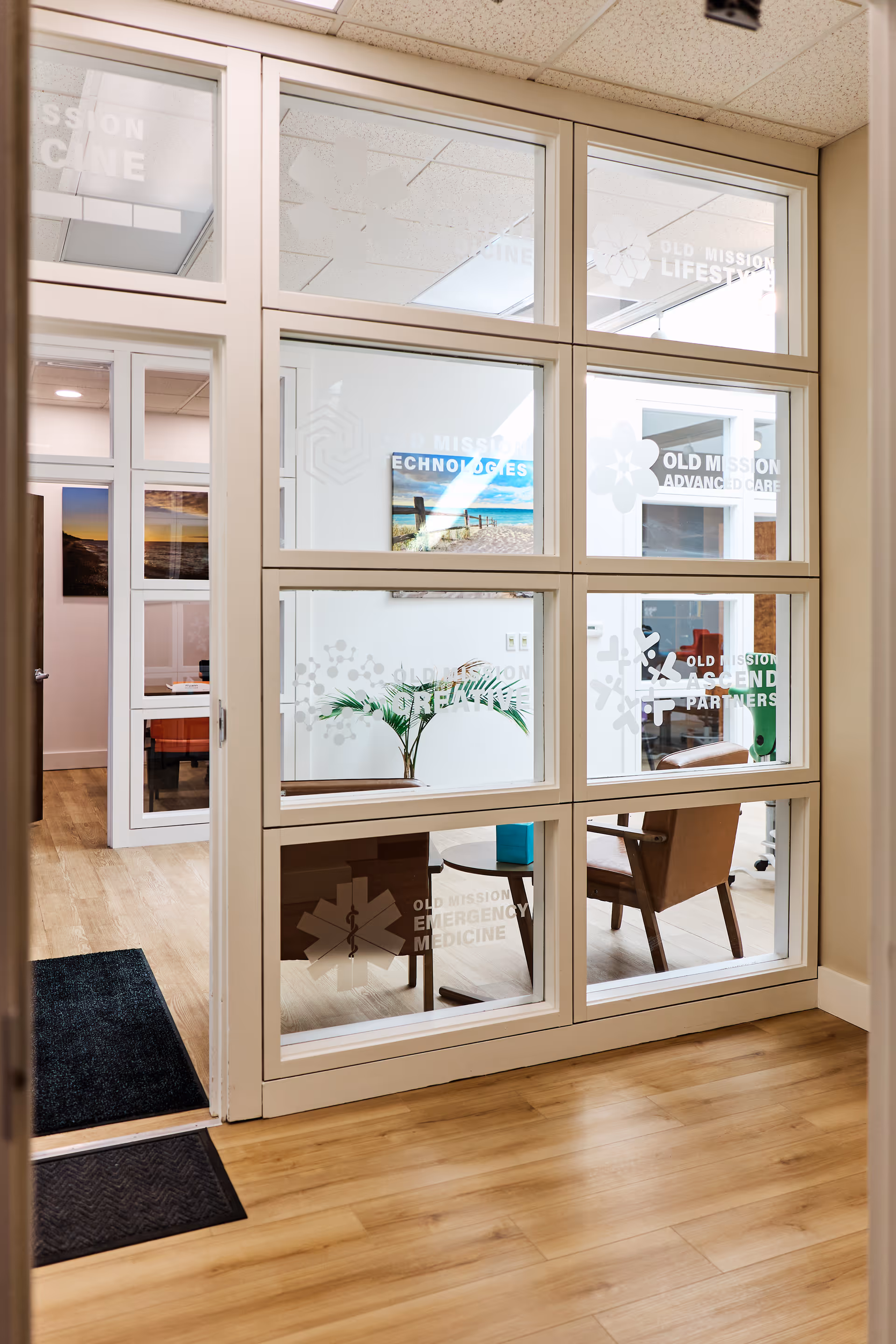 Interior lobby with glass partitions, seating, a plant, and frosted logos