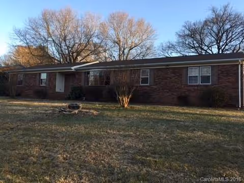 Single-story brick retirement center exterior with a lawn and leafless trees.