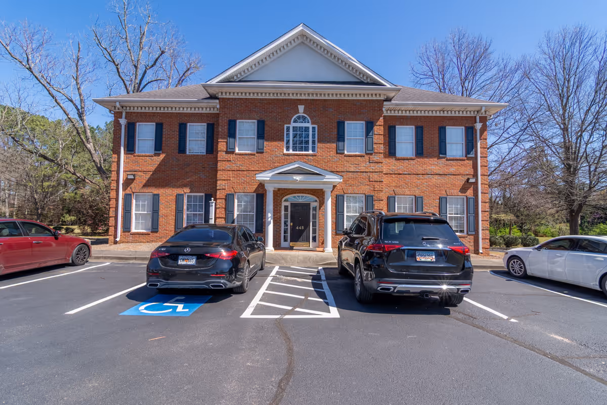 Brick two-story facility with front entrance and several cars parked in a lot.