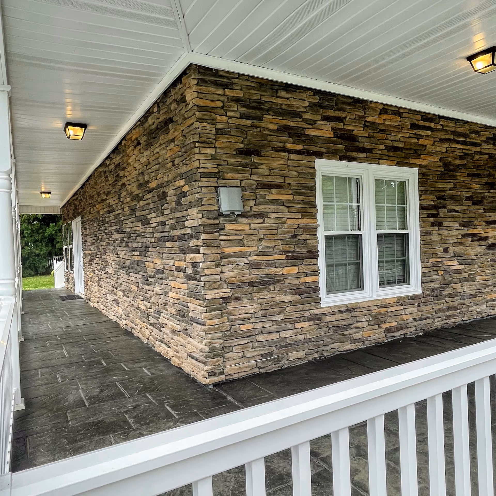 Stone exterior wall of Peace Haven Assisted Living with a covered porch and windows.
