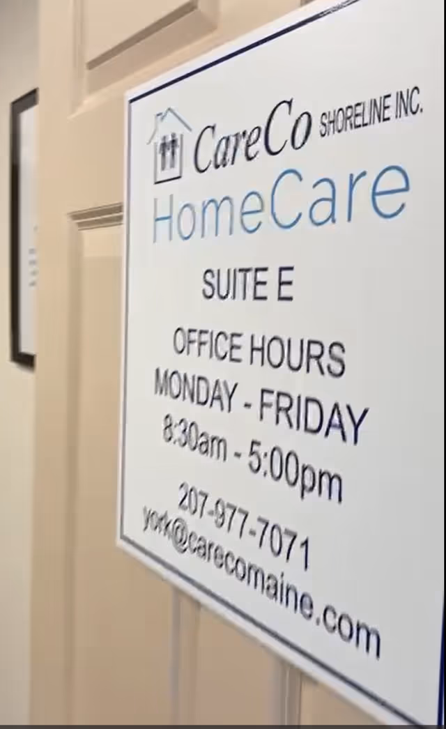 Indoor hallway with a CareCo HomeCare signboard listing office hours