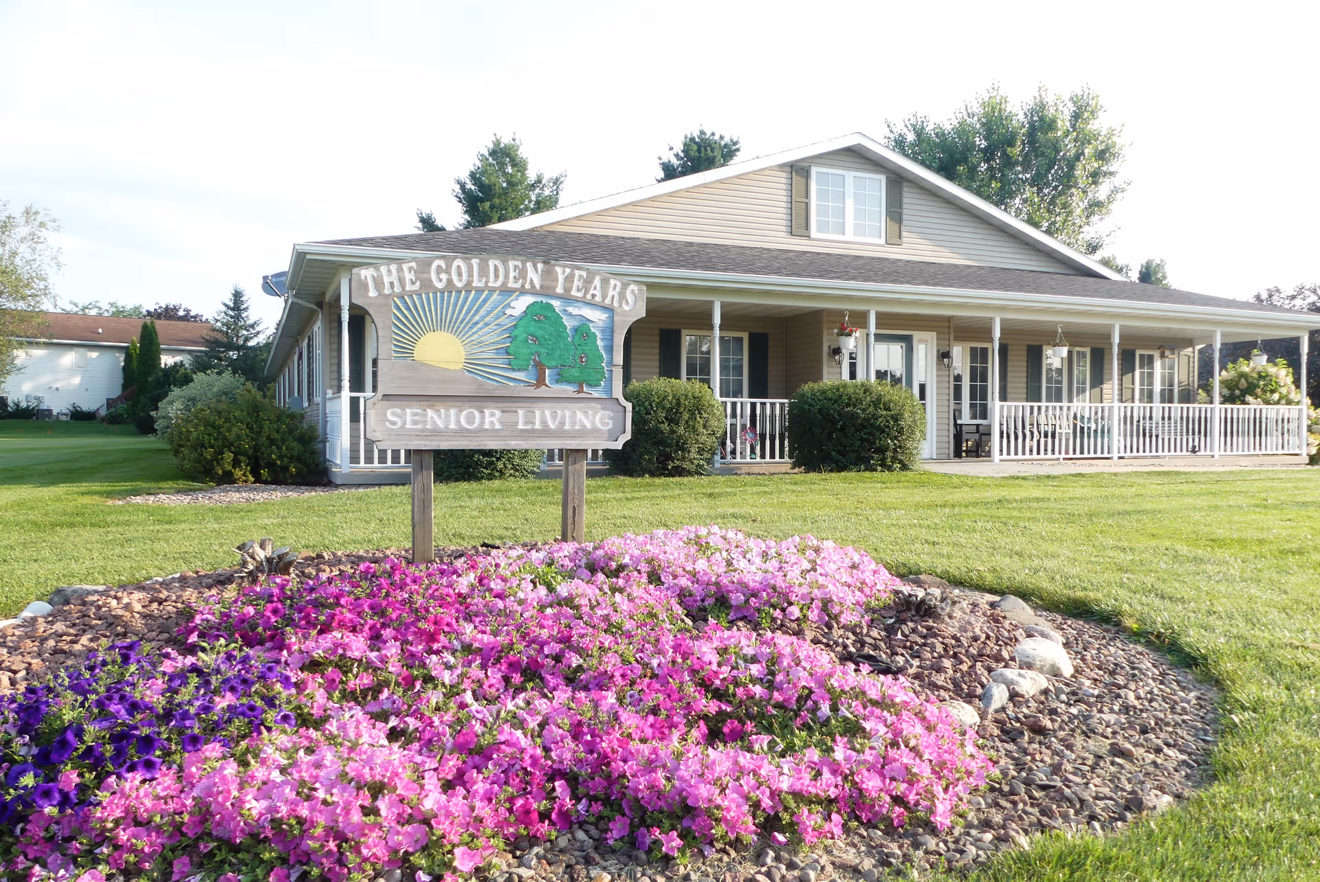 Front exterior of The Golden Years Senior Living building with sign and flowering bed.
