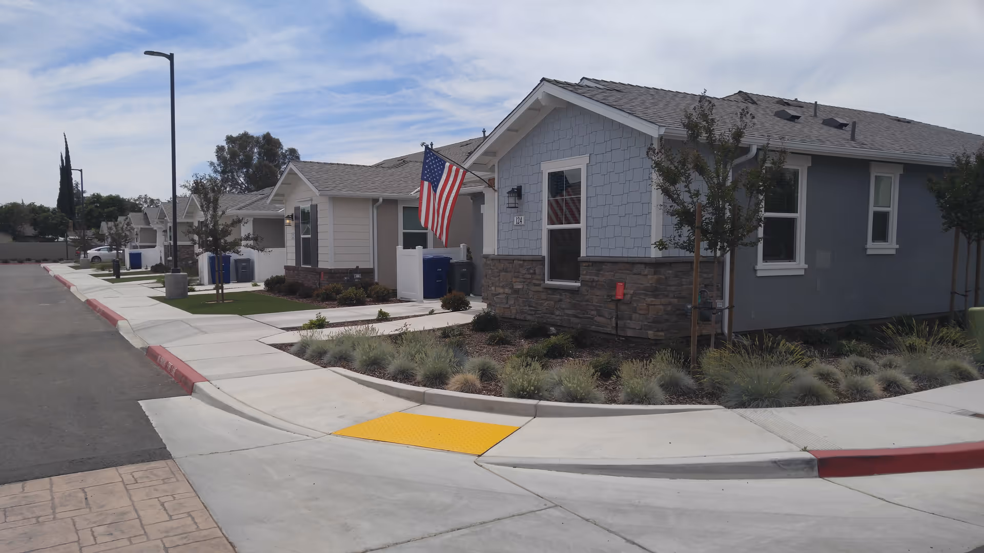 Single-story memory care facility exterior with landscaped front and American flag