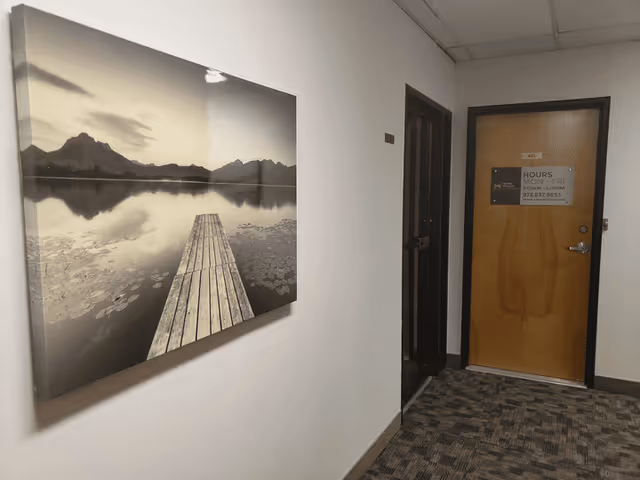 Hallway interior with a large black-and-white landscape artwork and a wooden door.