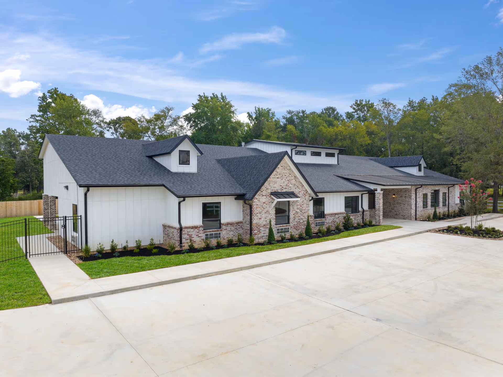 A modern, single-story assisted living building with brick and siding, landscaped front.