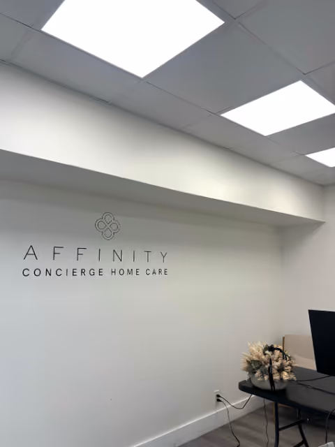 Reception area with Affinity Concierge Home Care sign, desk, and decorative flowers.
