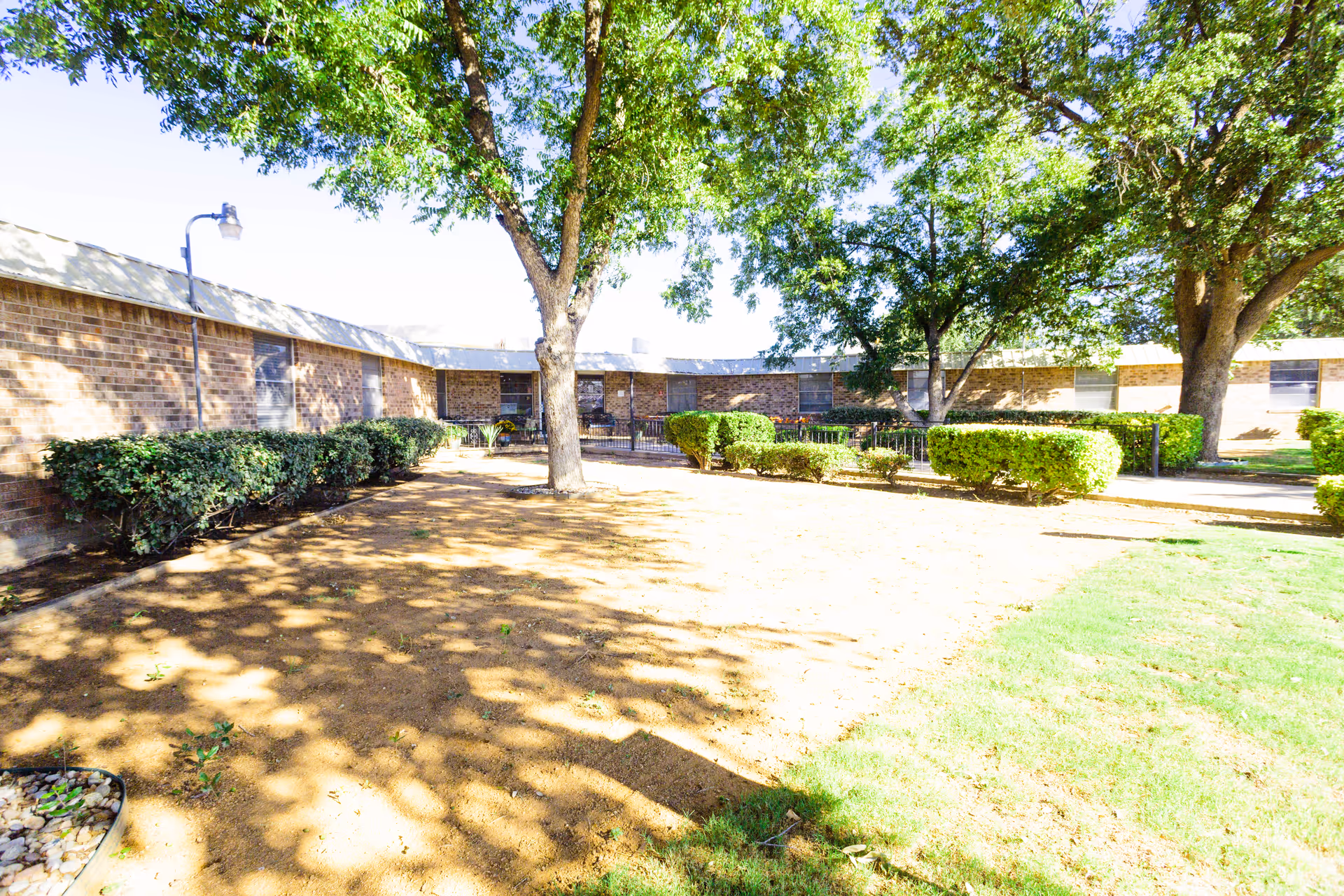 Outdoor courtyard at Rockwood Manor with trees, hedges, and a brick building.