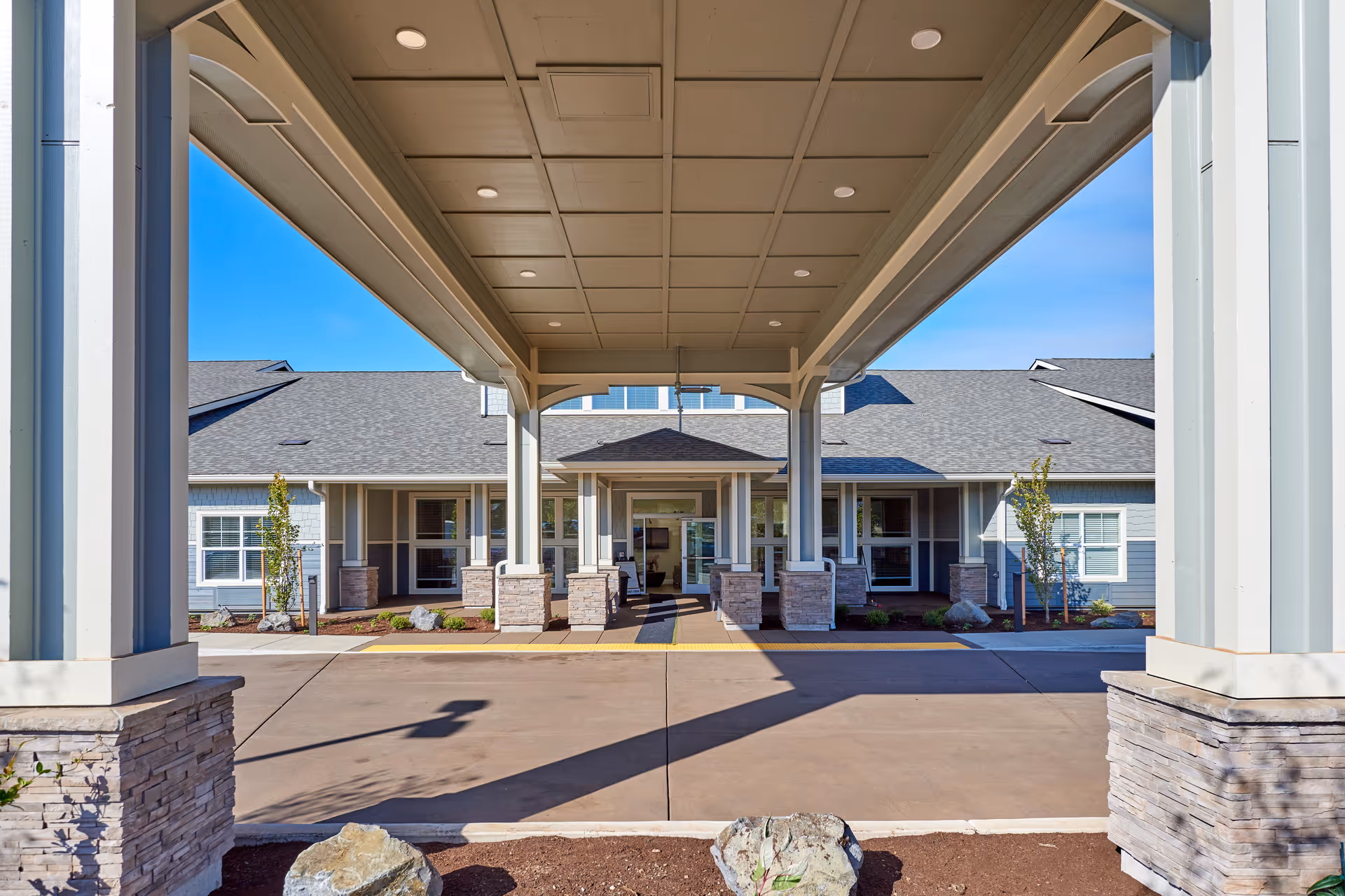 Front entrance of Battle Creek Memory Care featuring a covered driveway and stone pillar columns.
