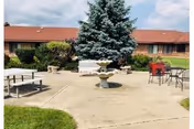 Outdoor courtyard with fountain, benches, and seating in front of a red-roofed building.