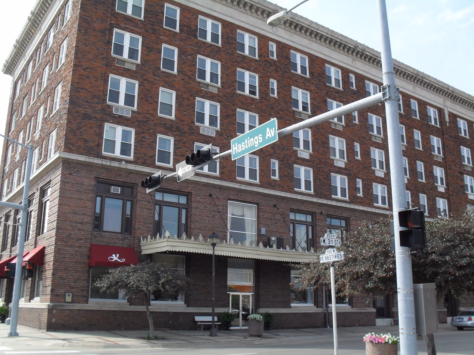 Brick, multi-story building on a street corner with storefronts and a Hastings Ave sign.