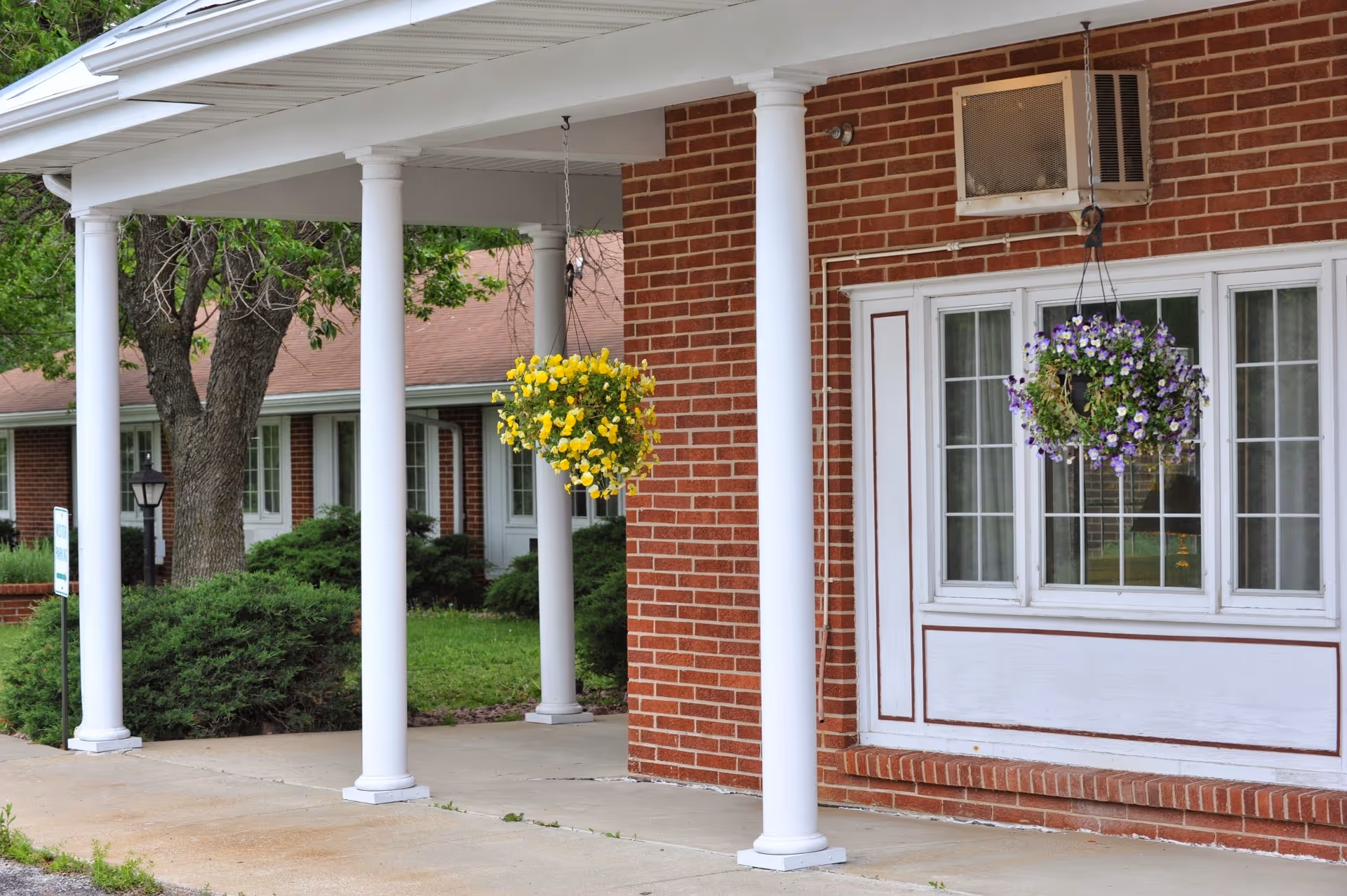 Exterior view shows a brick building with white columns and hanging flower baskets.