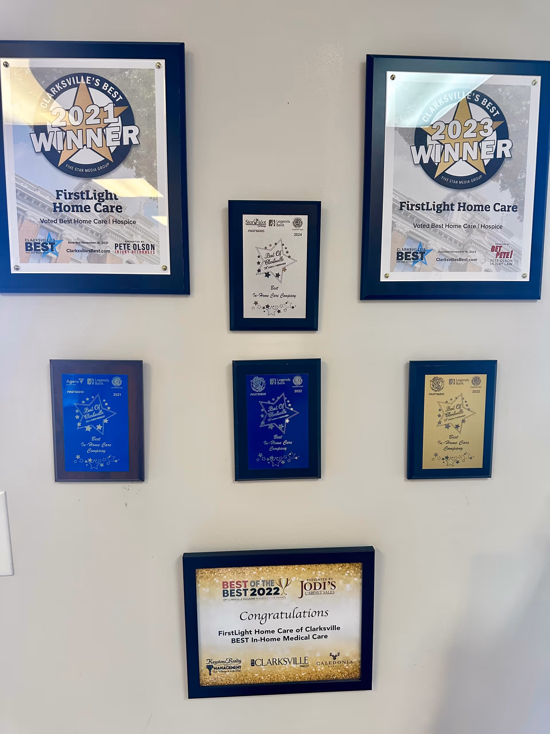 Wall with framed awards and certificates in a facility hallway.