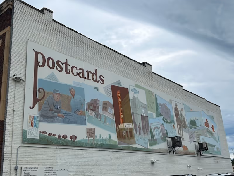 Exterior wall of a building featuring a large 'Postcards' mural.