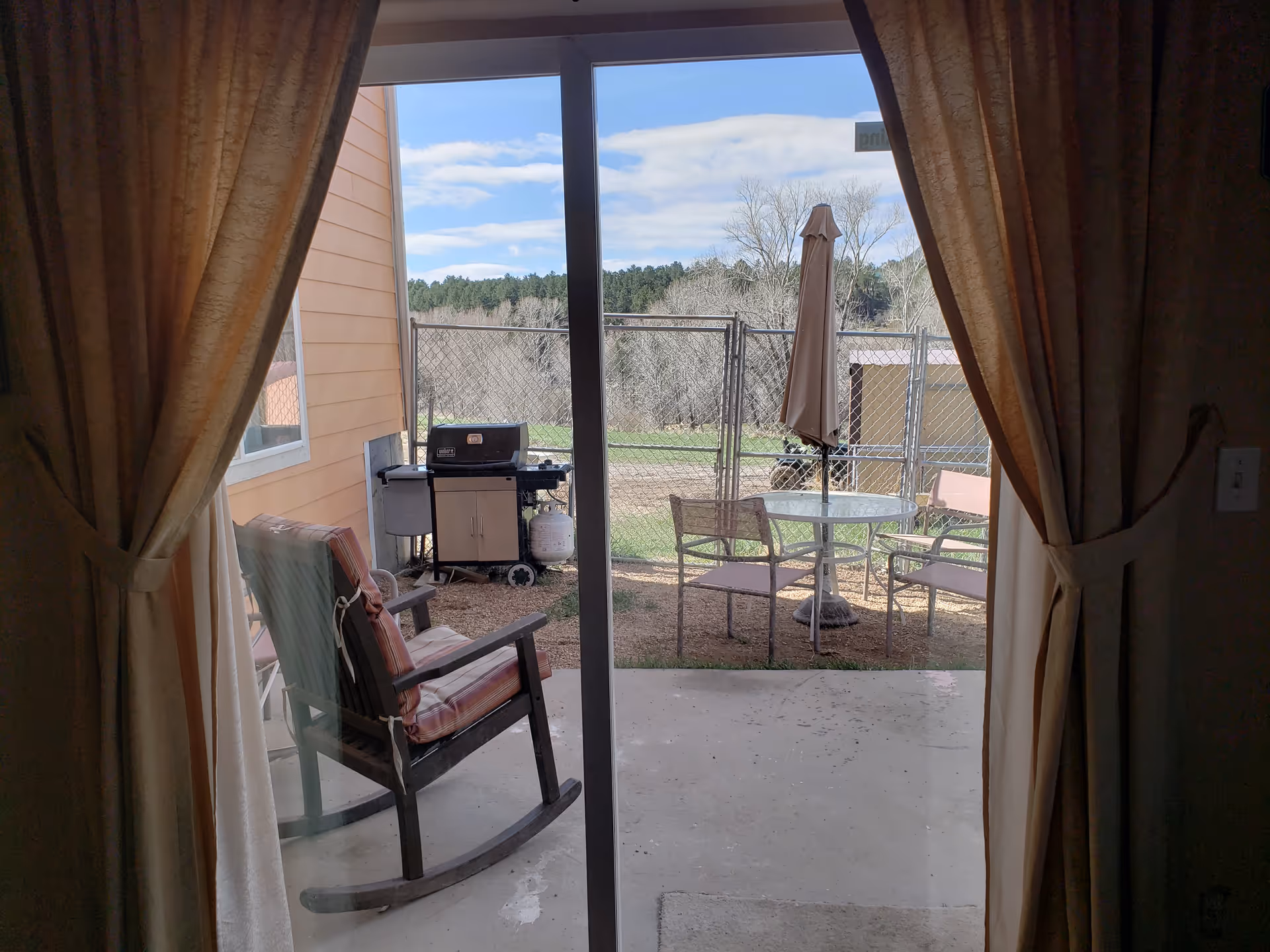 Sliding glass door opens to a fenced outdoor patio with seating and a grill.
