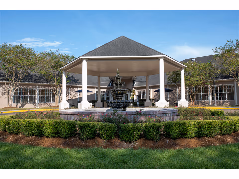 Exterior view of a senior living facility featuring a central fountain under a white pavilion.