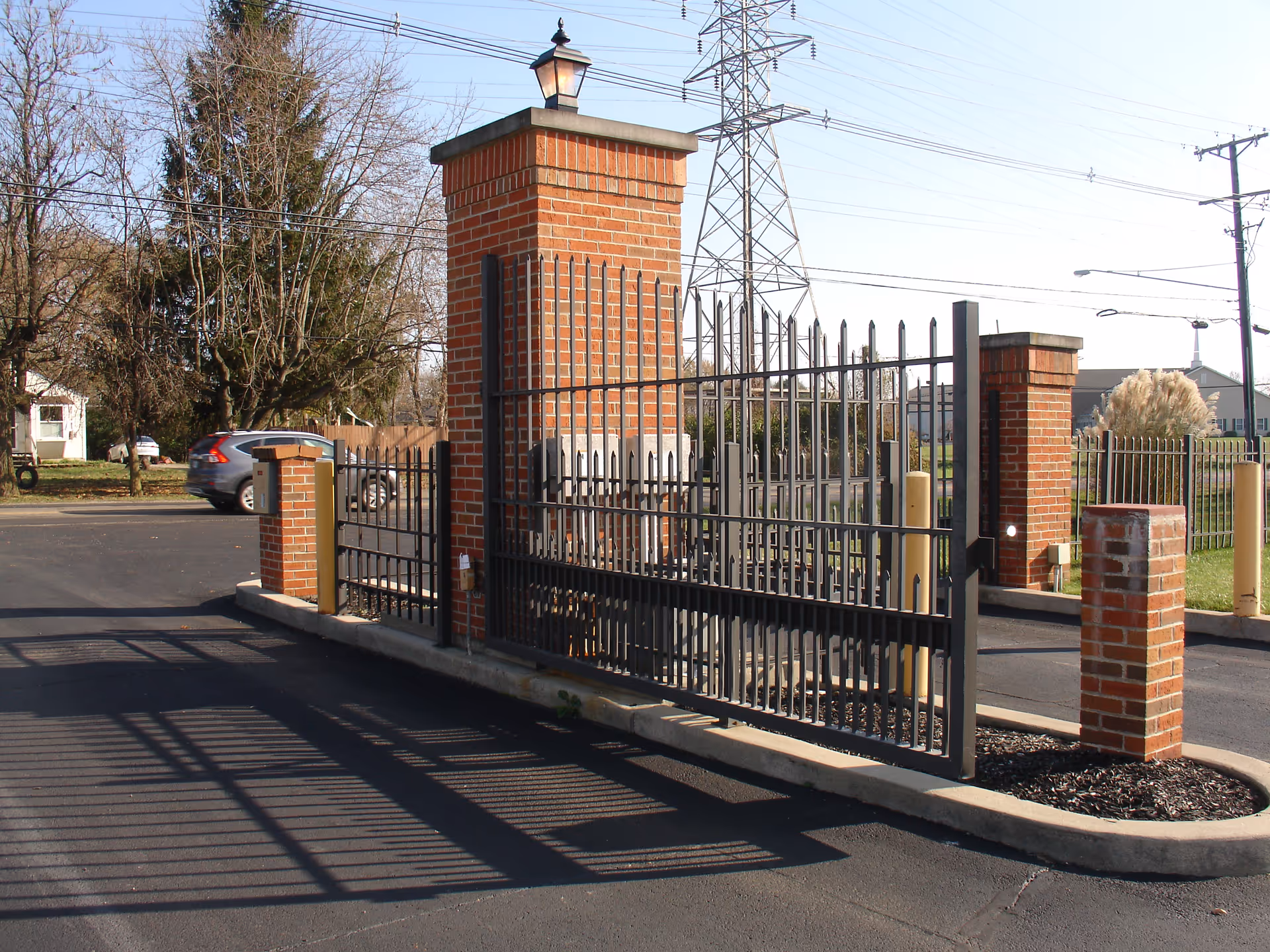 Gated brick entrance with tall iron fencing and driveway to a senior living facility.