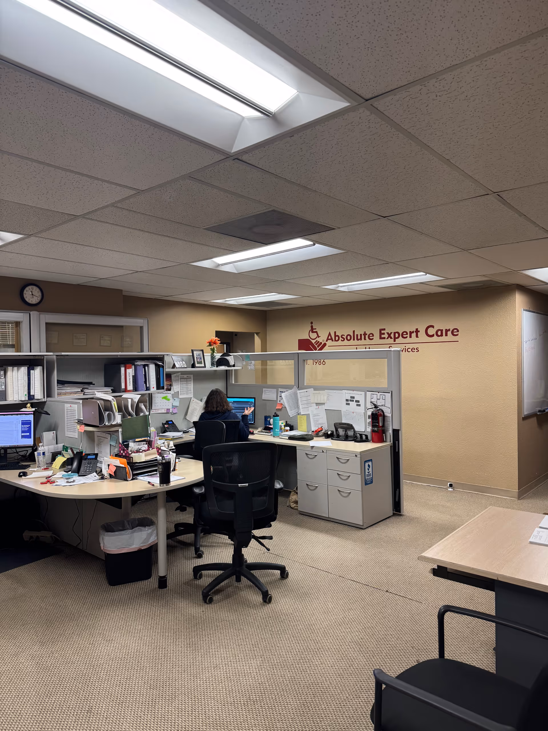 Office cubicles, desks, and a staff member in Absolute Expert Care's administration area.
