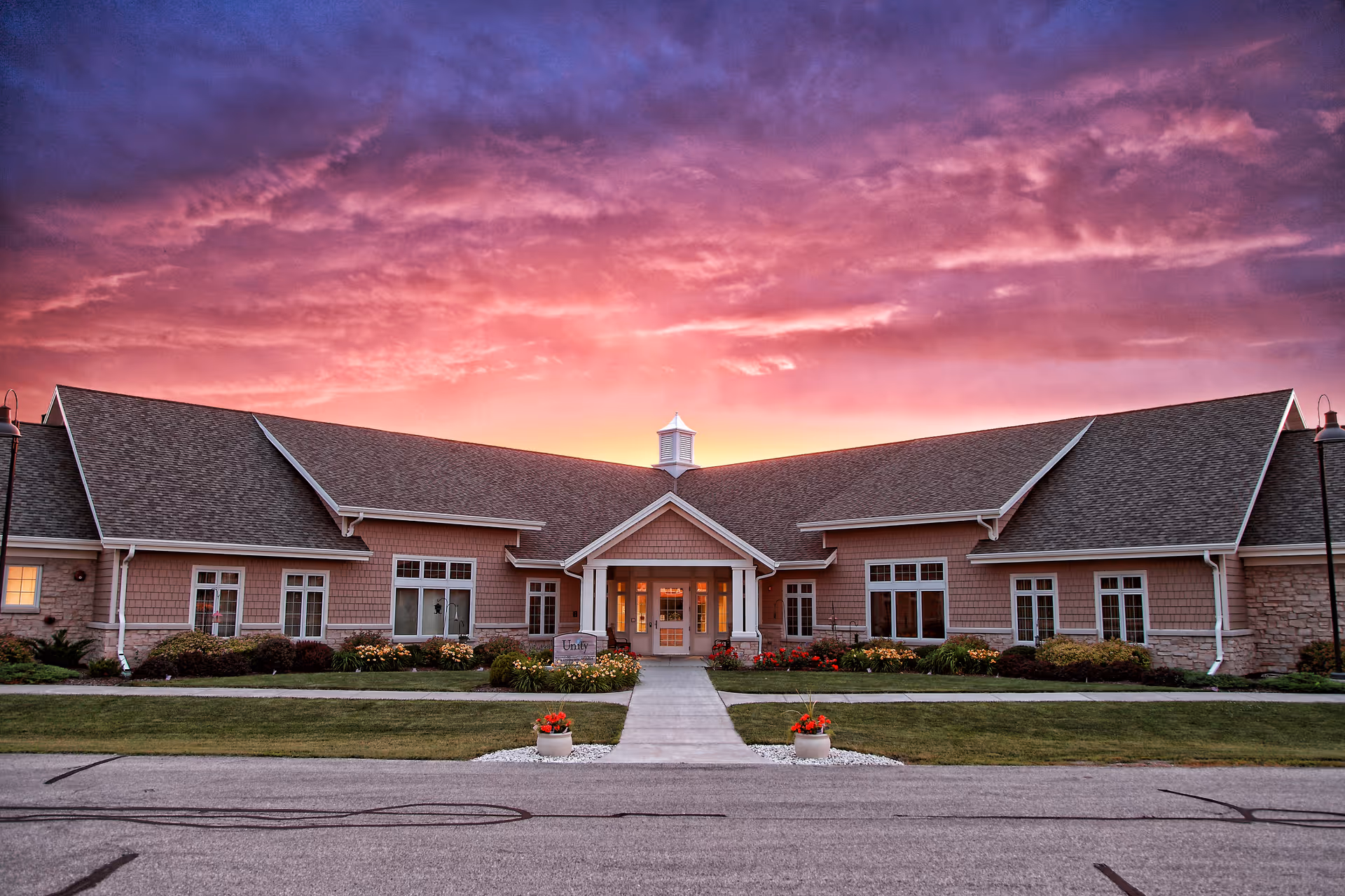 Sunset sky over Unity Hospice building with a manicured lawn and walkway.