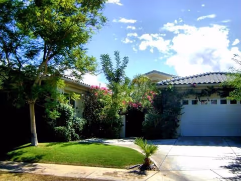 Front exterior of a single-story building with a garage, trees, and a manicured lawn.