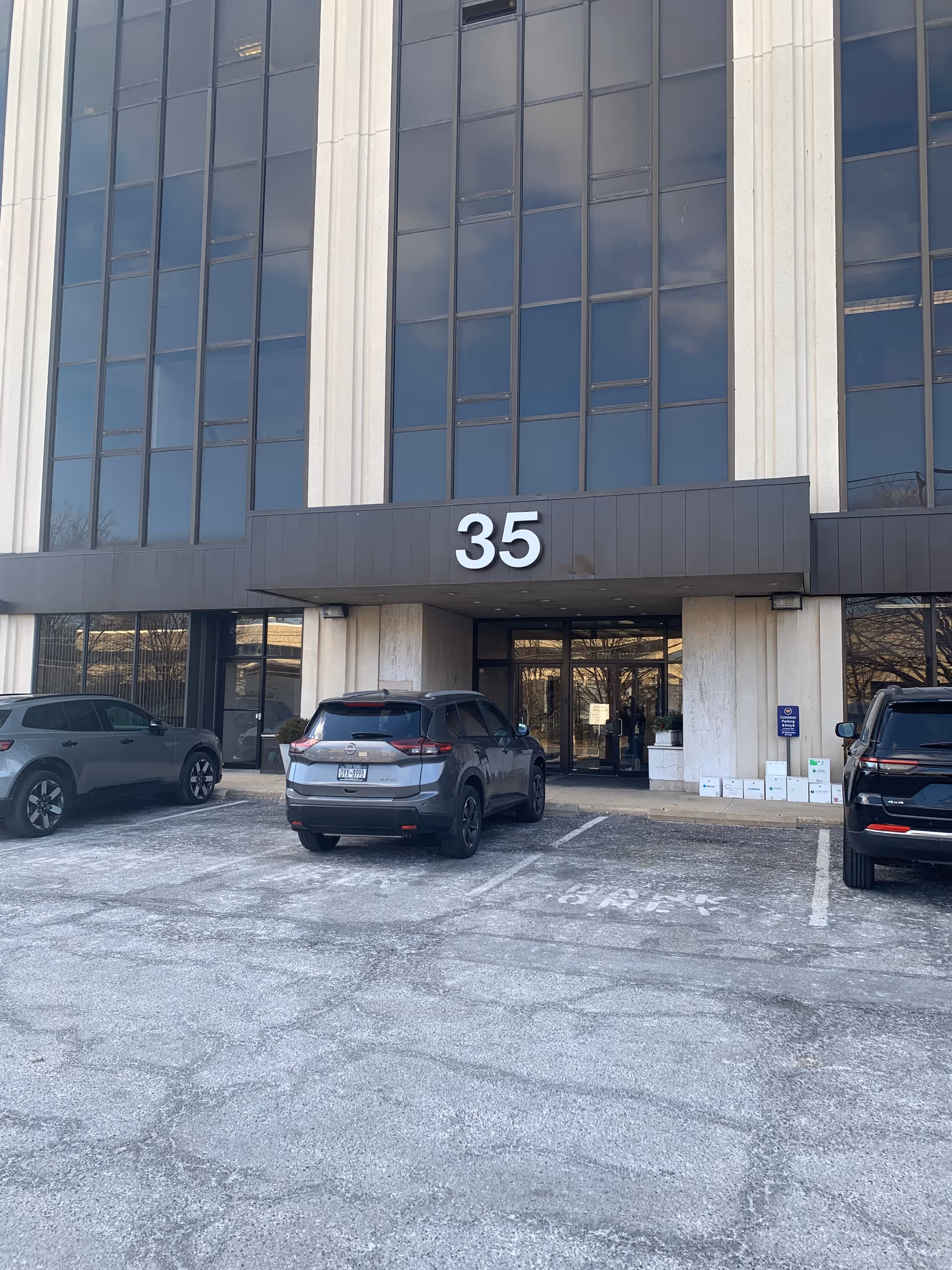 Exterior view of a tall building with the number 35 and parked cars in front.