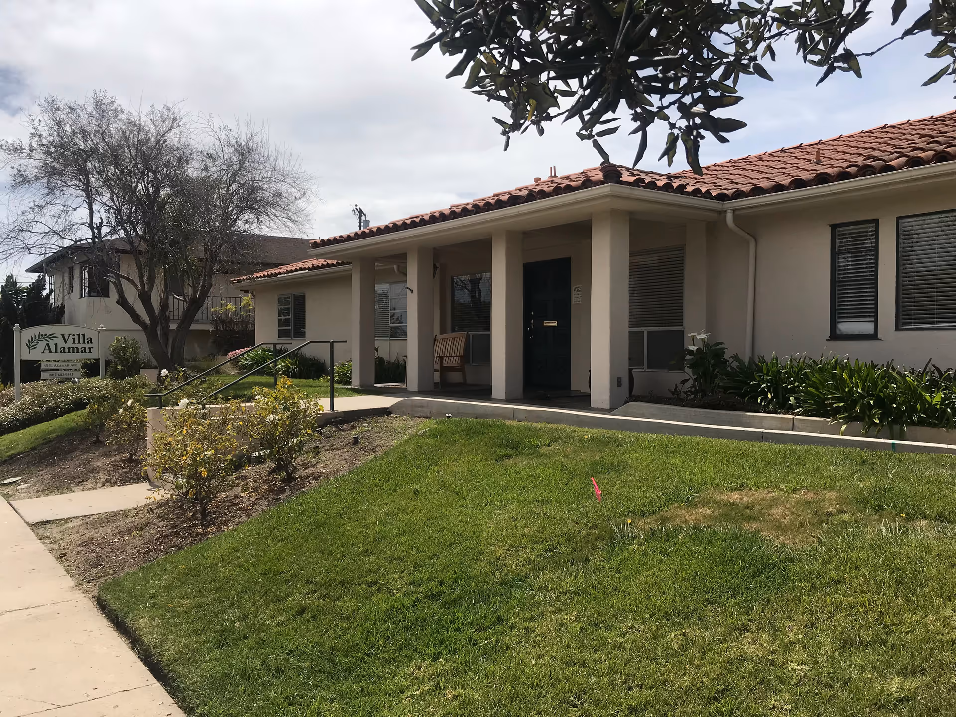 Exterior view of Villa Alamar, a single-story senior living facility with front entry and sign.