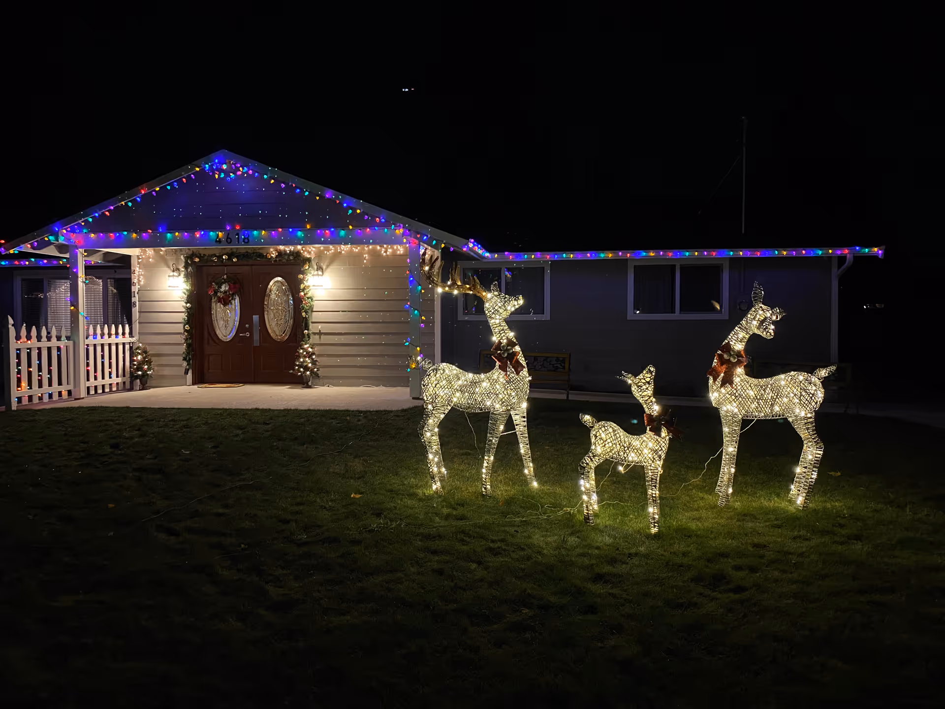 Night exterior of a decorated senior living home with Christmas lights and illuminated reindeer displays.