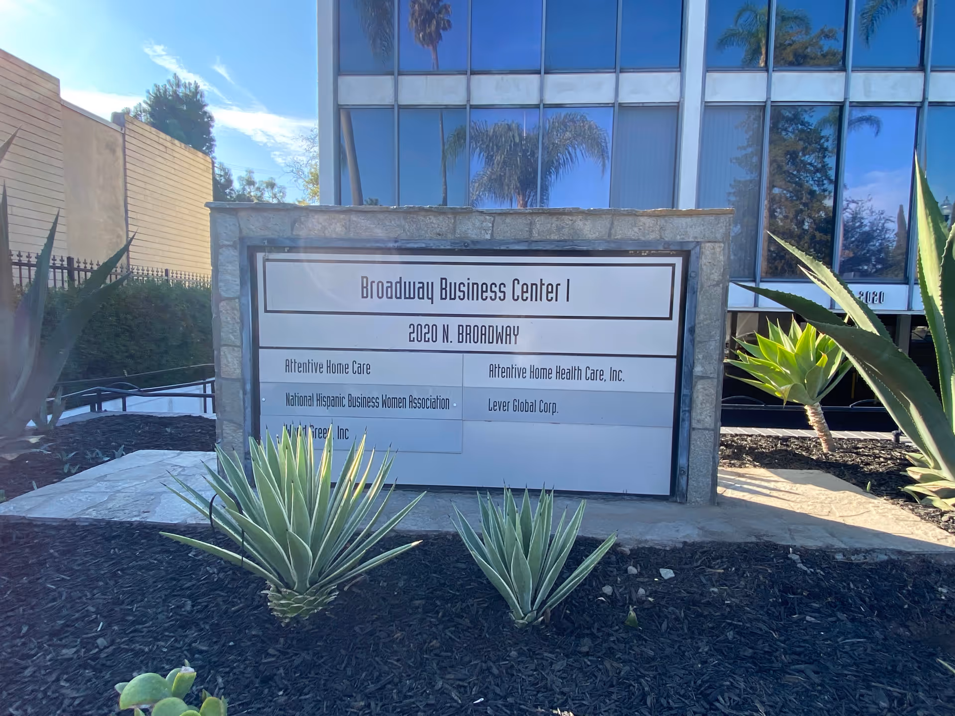 Stone sign reading Broadway Business Center I and Attentive Home Care in front of glass building.