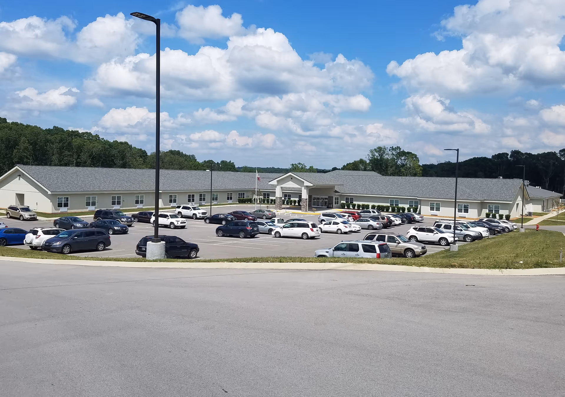 Single-story care facility with a long front entrance and a busy parking lot.