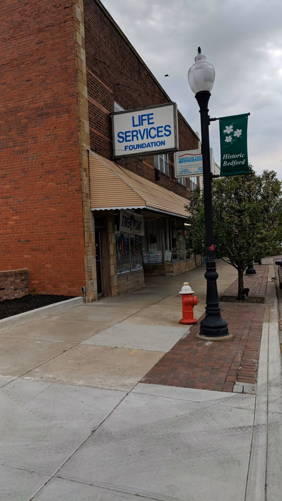 Brick building along sidewalk with Life Services Foundation sign and historic Bedford banner.