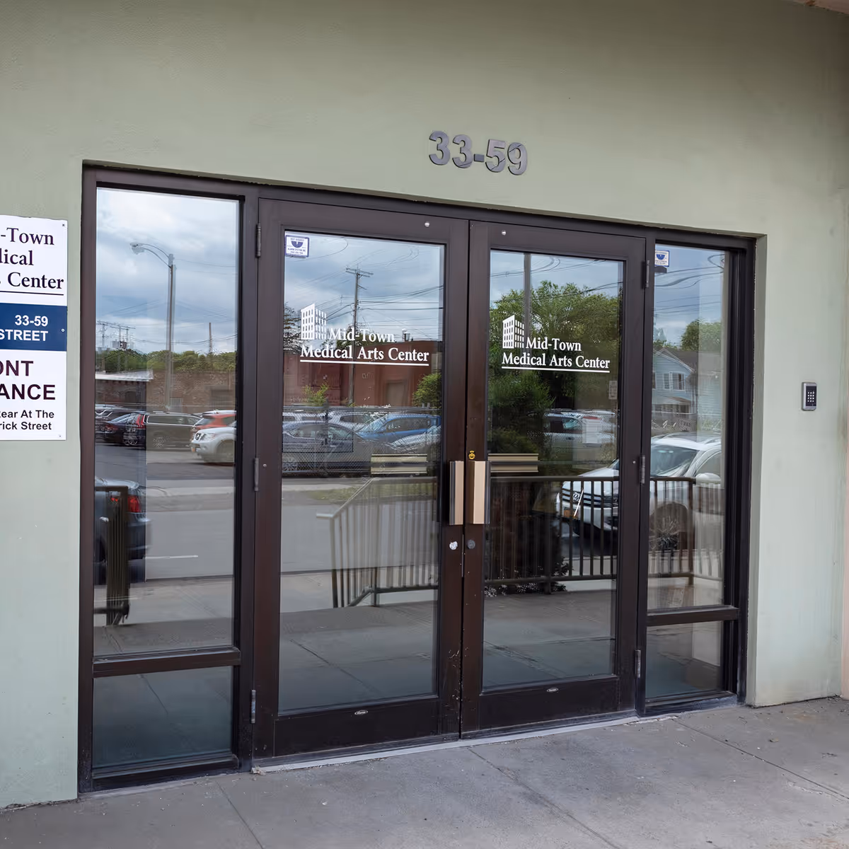 Front entrance with glass doors labeled Mid-Town Medical Arts Center and the address 33-59