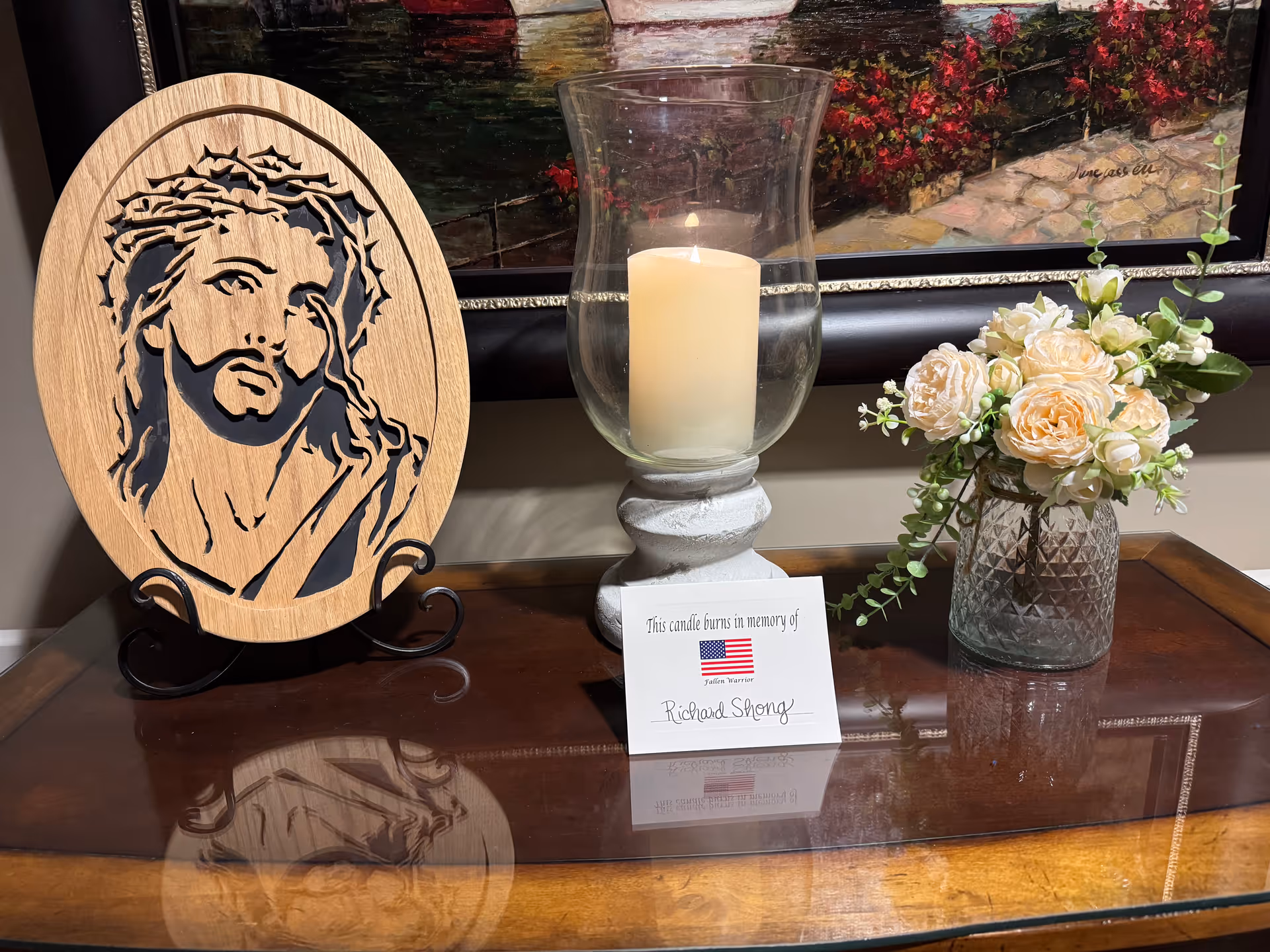 Memorial candle and floral arrangement on a wooden table in a hospice interior.