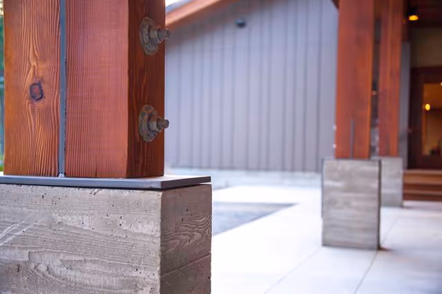 Exterior view of a facility entrance with wooden posts and concrete bases.