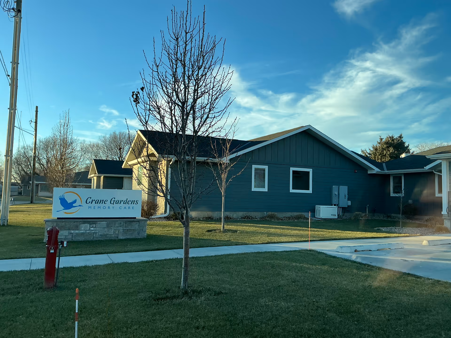 The Crane Gardens memory care facility exterior shows a blue building with a sign.